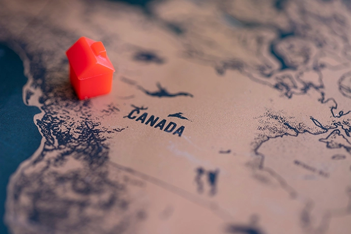 Paper map of Canada with small plastic house toy on it